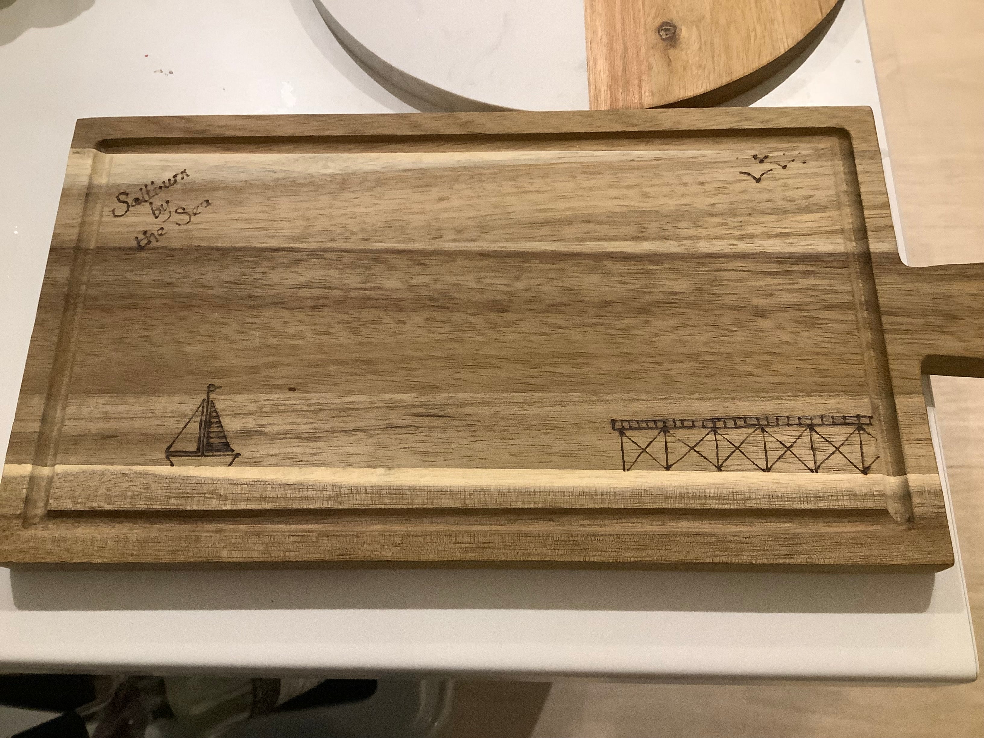 Cartoon illustration of Saltburn Pier and yacht, and the words Saltburn by the Sea, coastal art gift. Acacia wood with hand drawn  image  with pyrography
