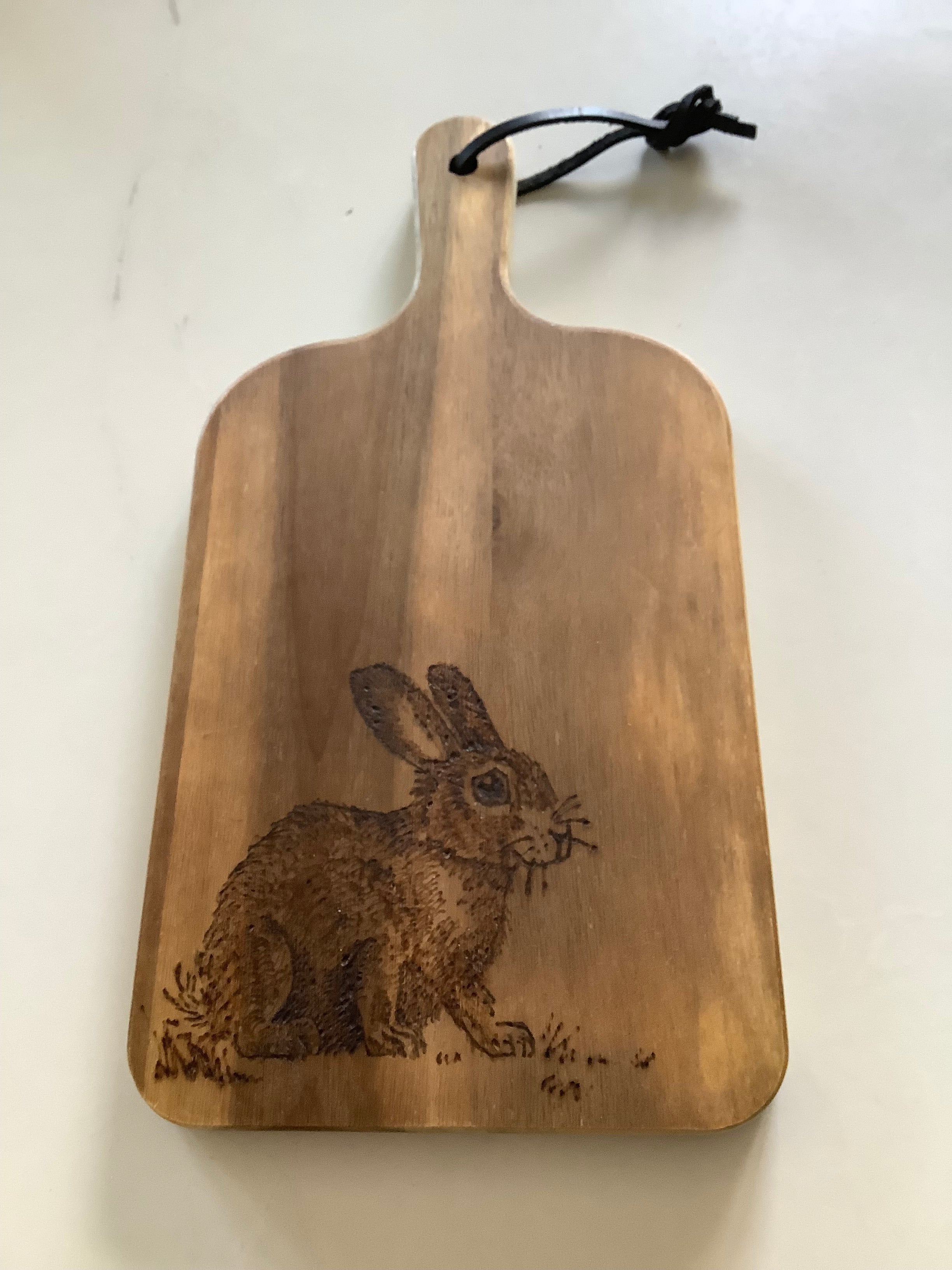 Hand-decorated with pyrography, this Acacia wood serving board has a Rabbit design, handcrafted coastal gift