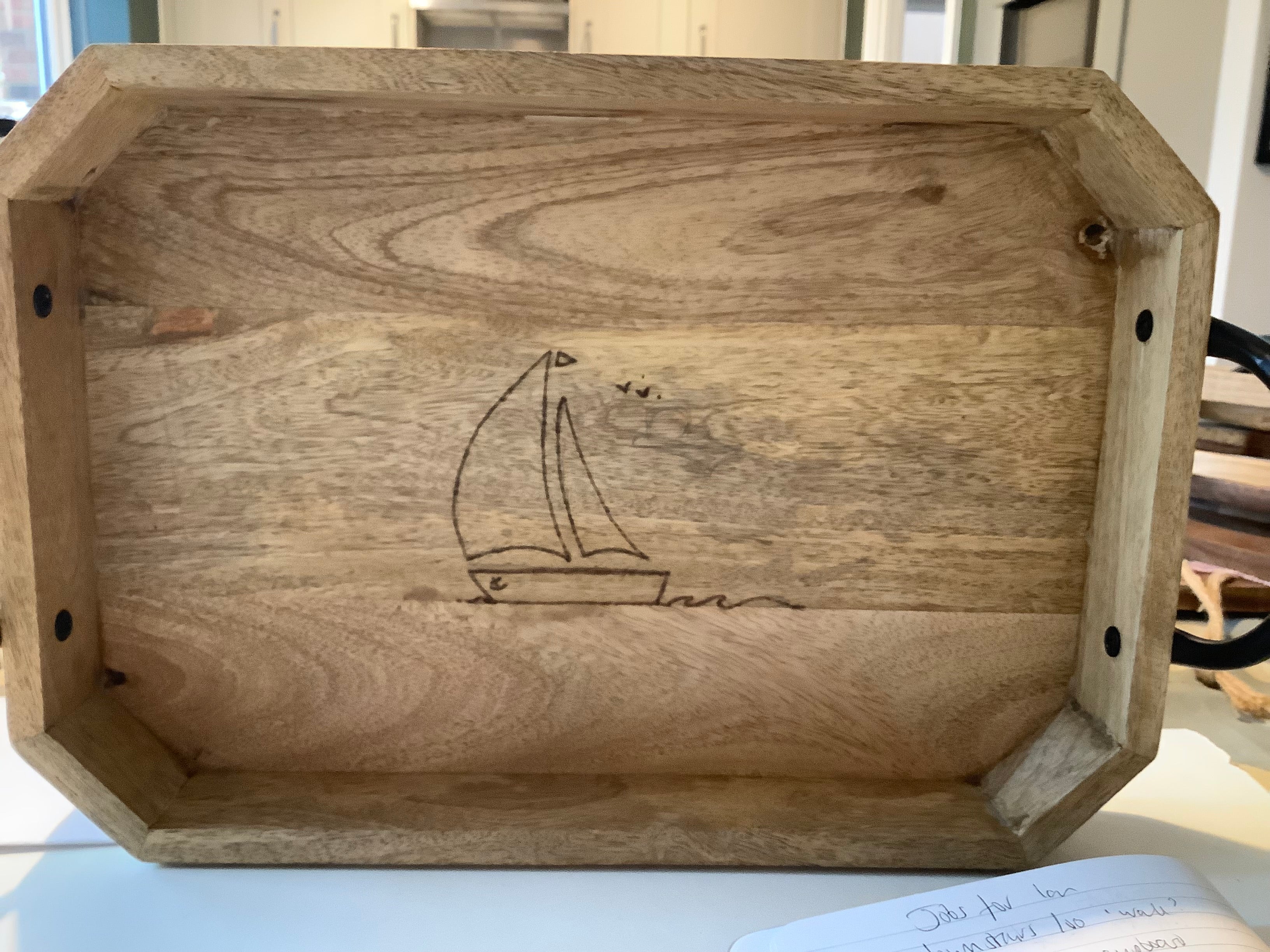 Large Acacia tray with diagonal corners and Iron handle details. Hand-decorated using pyrography, with a yacht design. Perfect coastal home gift