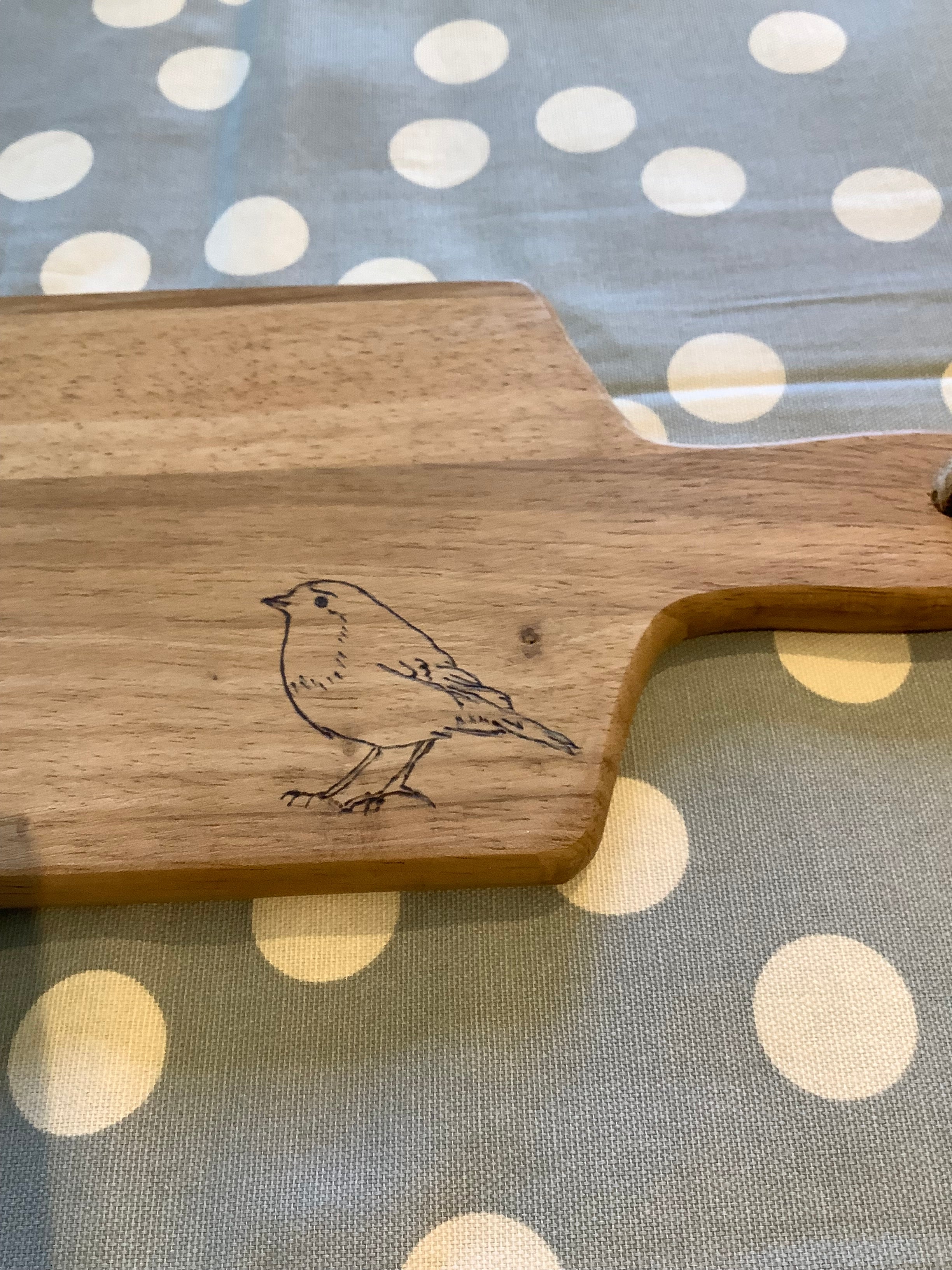 Hand-decorated using pyrography, this long wooden serving board with a simple line drawing of a robin, handcrafted coastal gift