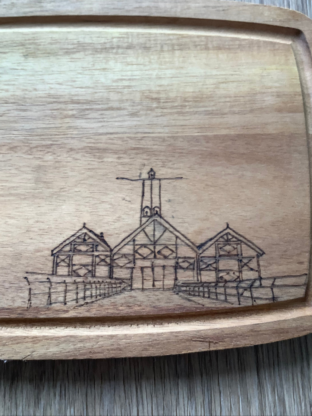Close-up of hand-burned pyrography illustration of Saltburn Pier amusements on a small acacia wood serving board by Saltburn Coastal Art