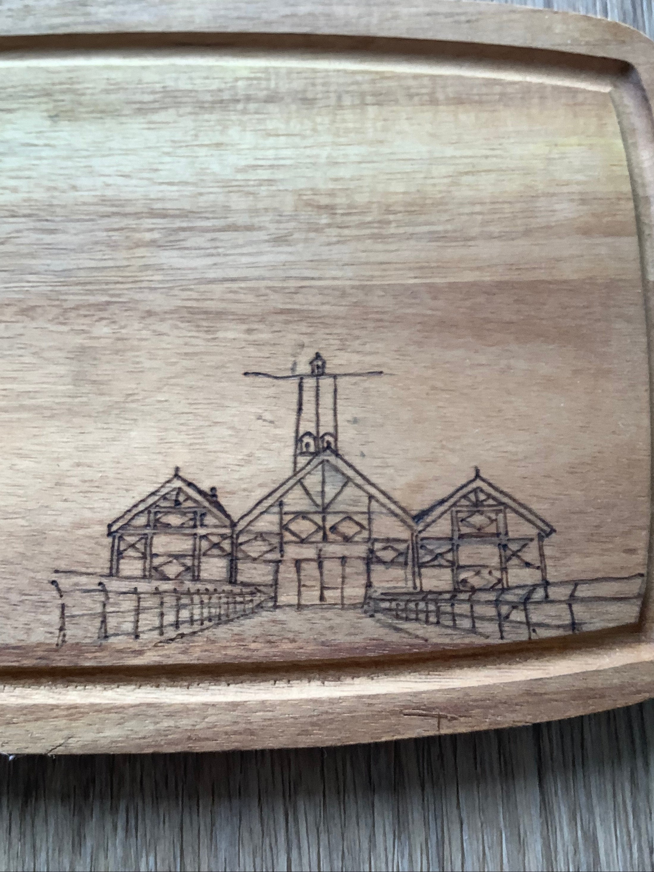Close-up of hand-burned pyrography illustration of Saltburn Pier amusements on a small acacia wood serving board by Saltburn Coastal Art